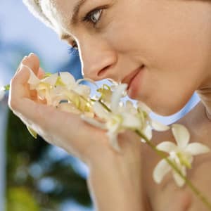Close up of Caucasian mid-adult woman holding white orchid flowers up to face.
